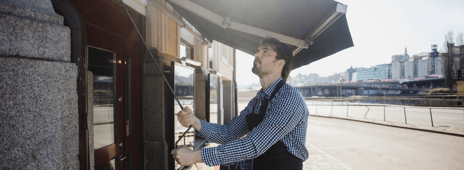 Man standing outside his business securing the awning